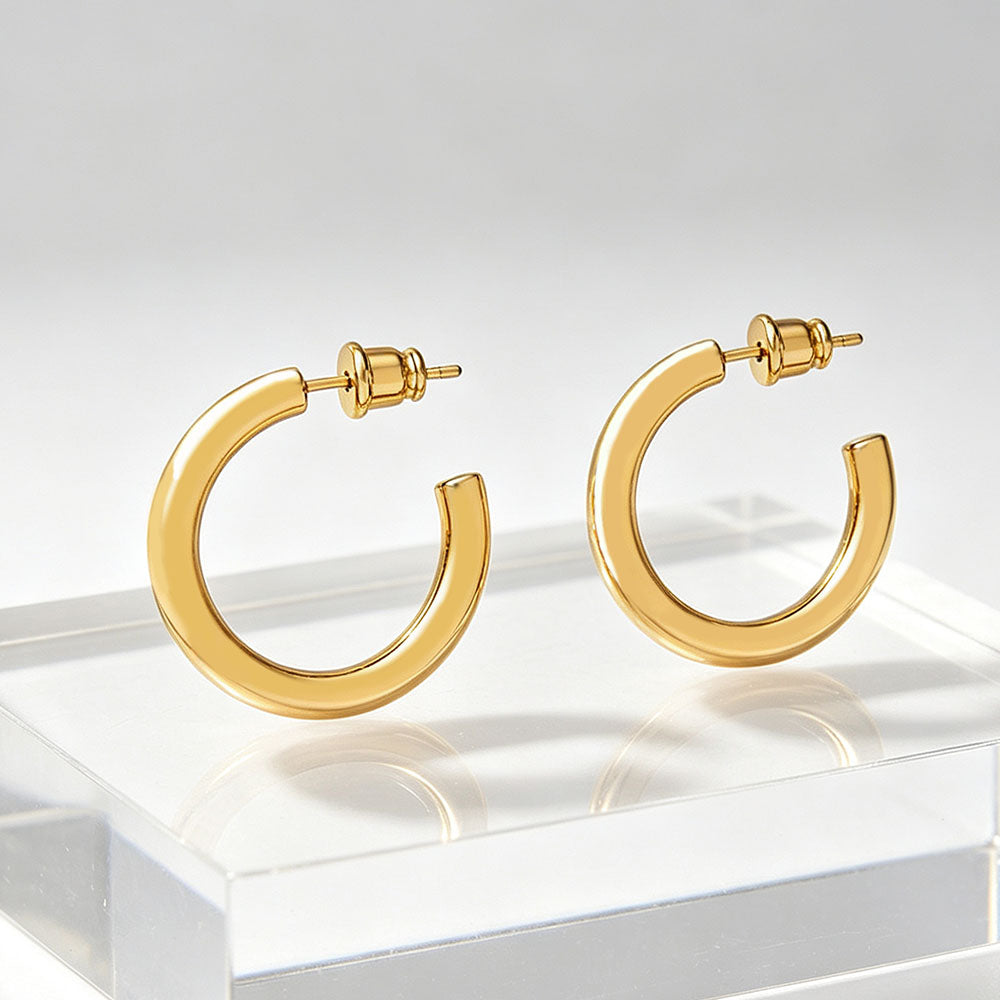 18K gold chunky hoop earrings displayed on clear acrylic stand, minimalist jewelry photography