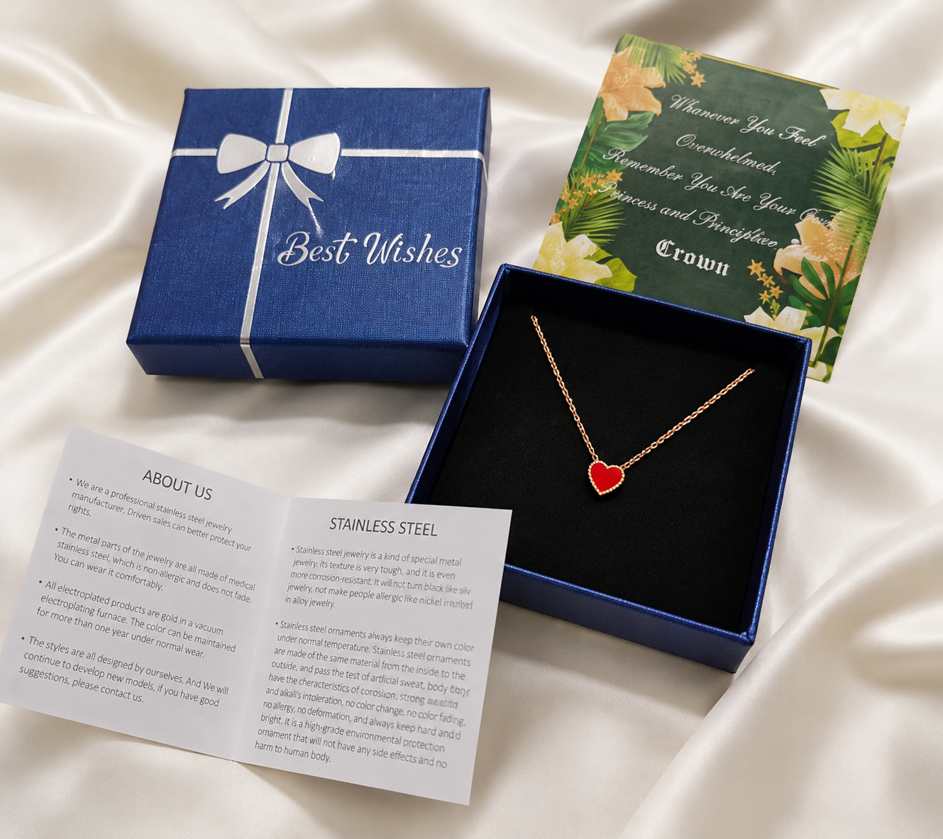 Red heart necklace in blue Best Wishes gift box with greeting card and stainless steel care booklet on white satin