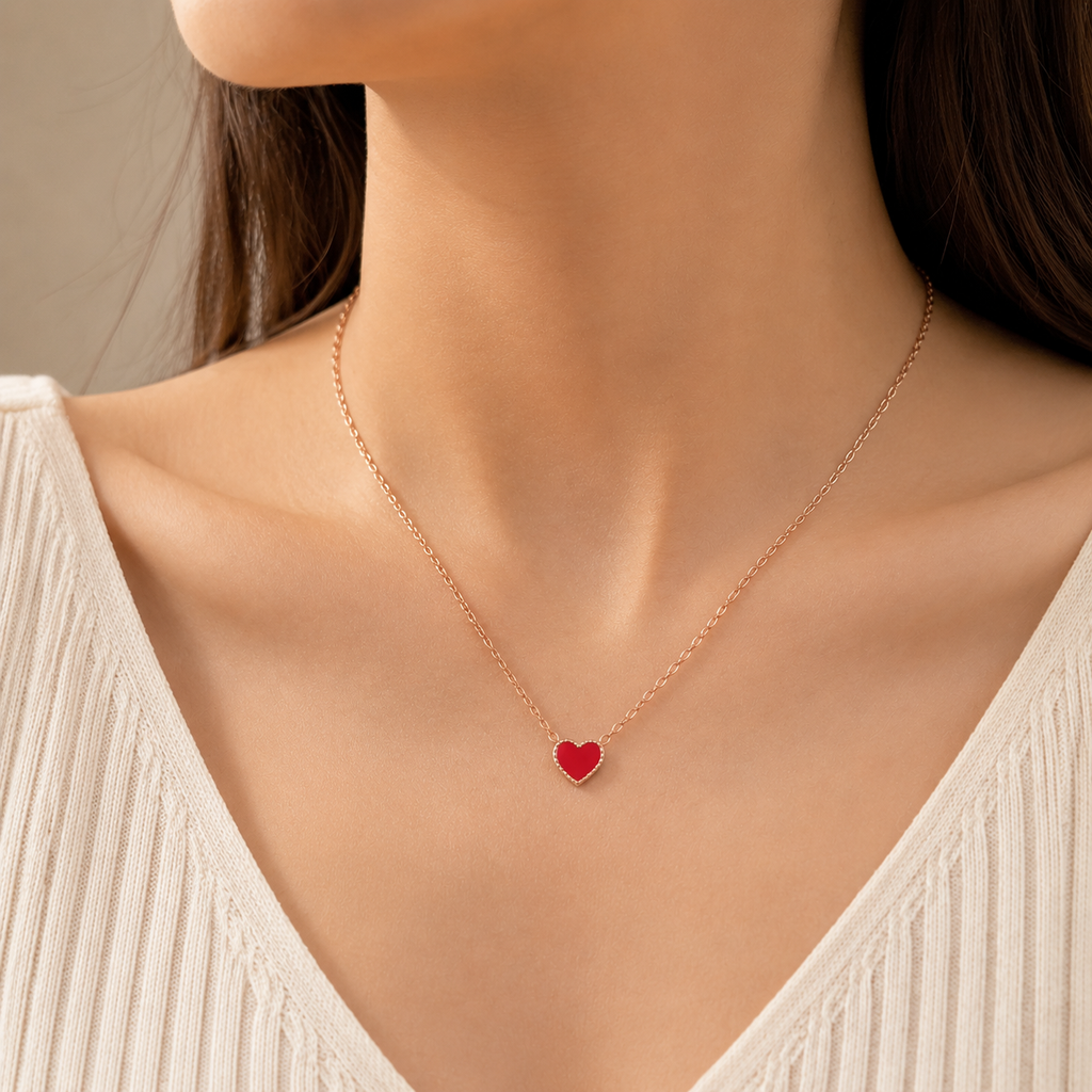 Woman wearing dainty red enamel heart pendant necklace on rose gold chain, minimalist everyday jewelry, V-neck white top