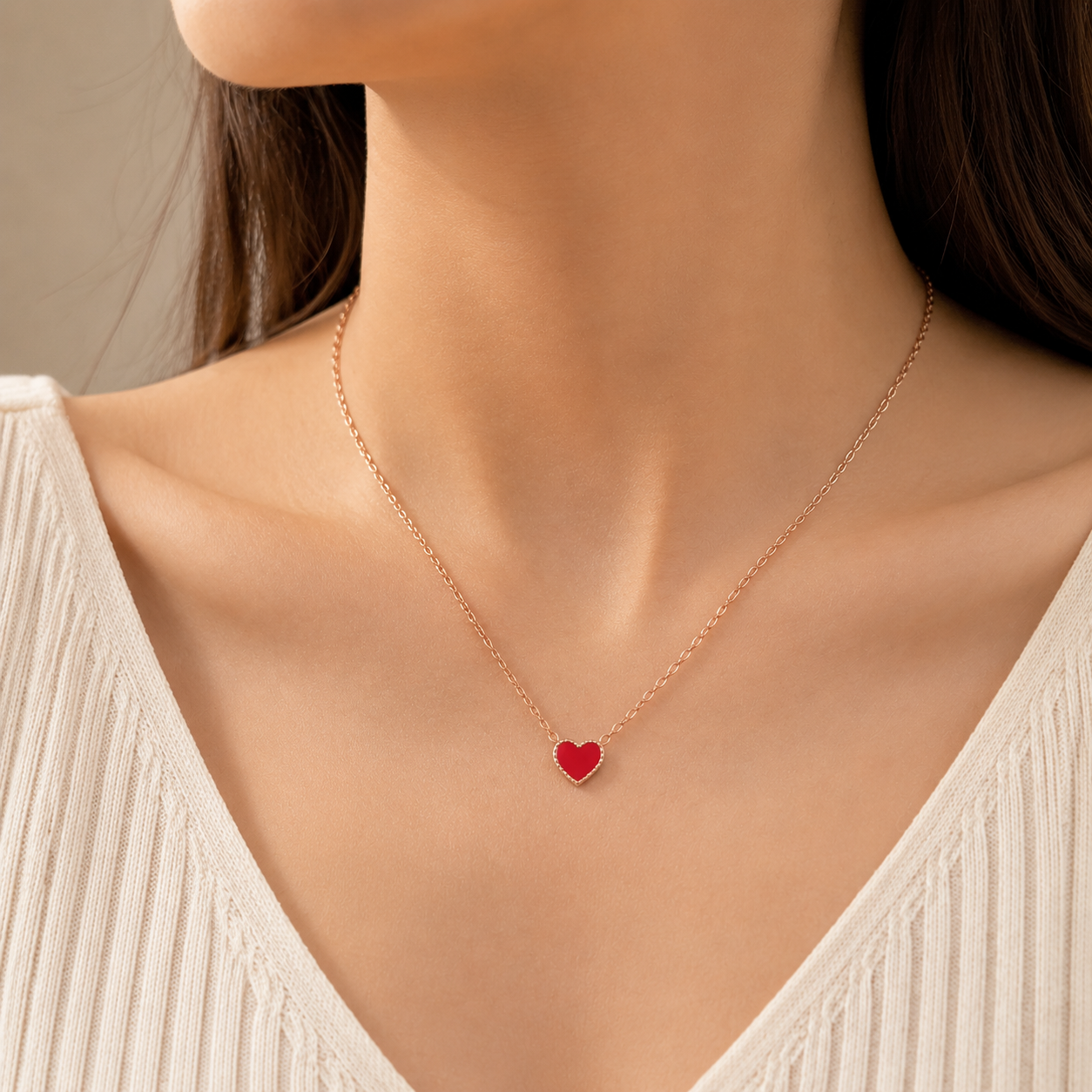 Woman wearing dainty red enamel heart pendant necklace on rose gold chain, minimalist everyday jewelry, V-neck white top